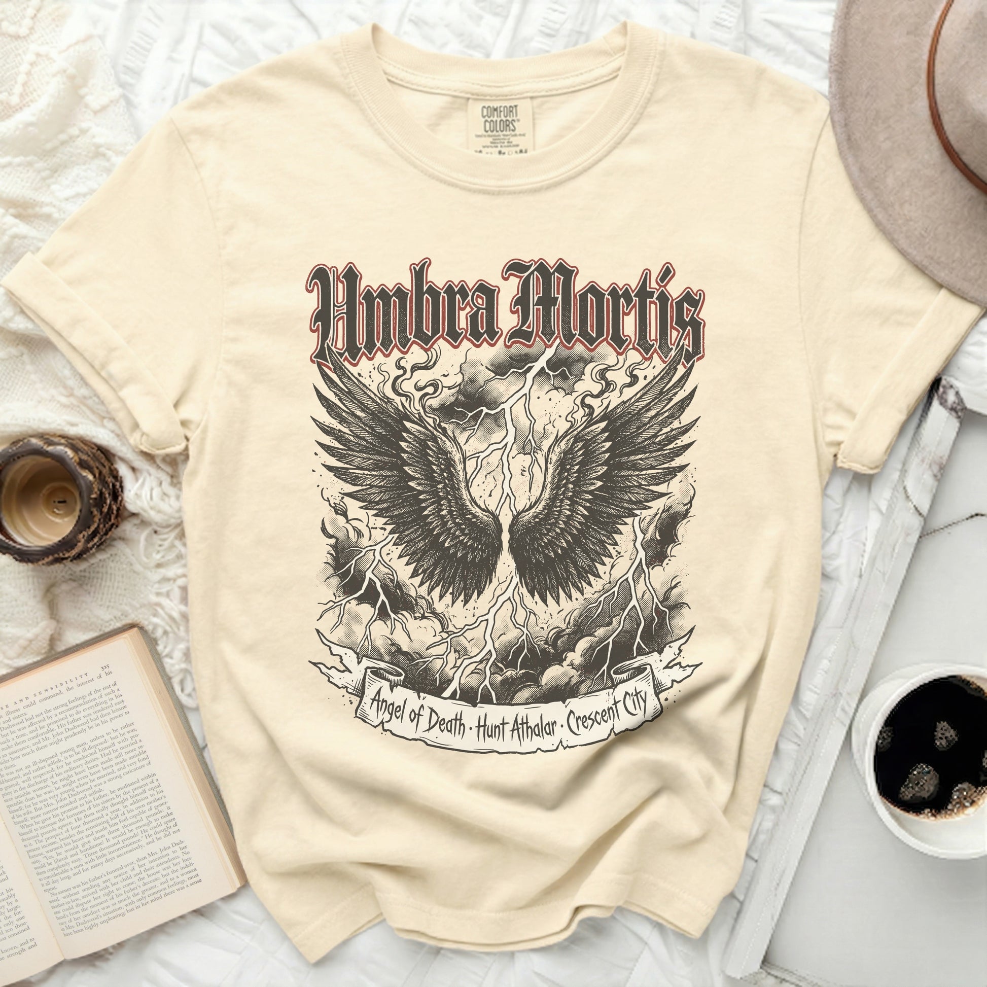 Cream t-shirt with black winged skull and text "Umbra Mortis".