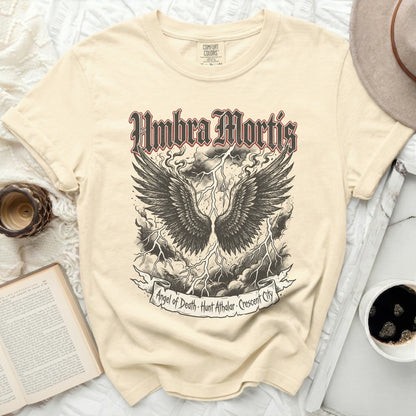 Cream t-shirt with black winged skull and text "Umbra Mortis".