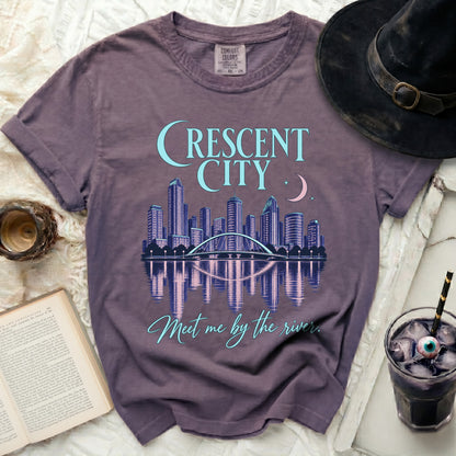 Purple t-shirt with "Crescent City" skyline graphic and "Meet me by the river" text.