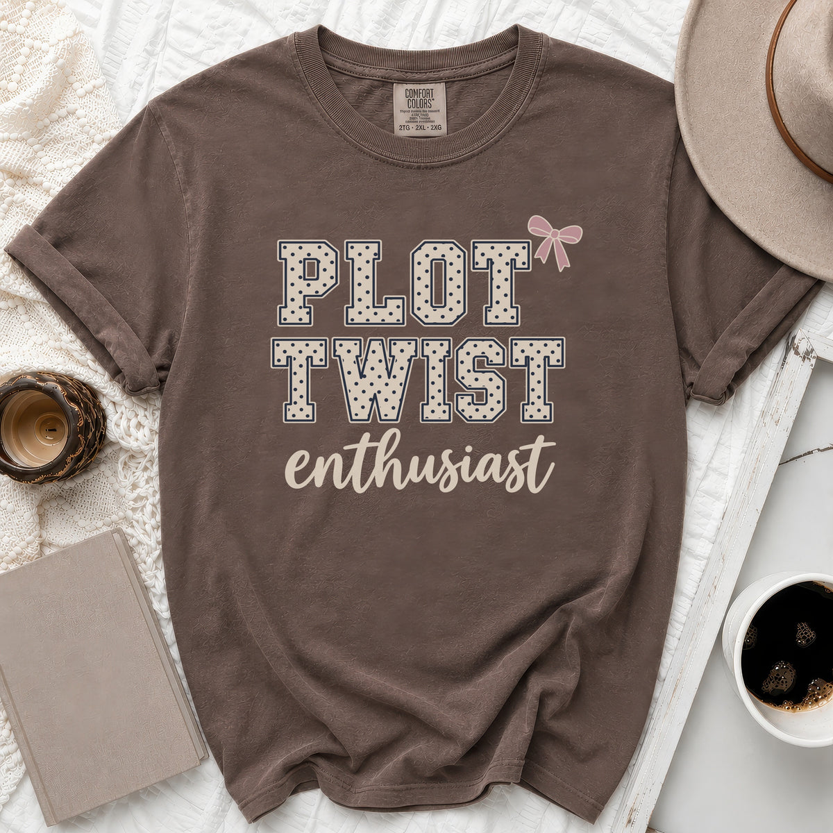 Brown t-shirt with "Plot Twist Enthusiast" text and pink bow.