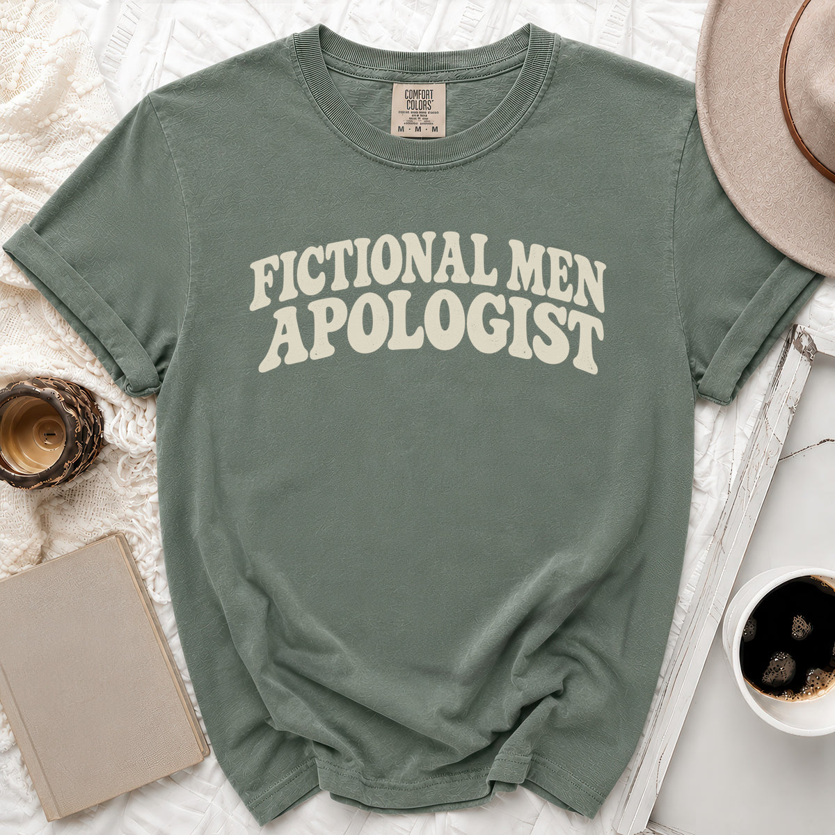 Sage green t-shirt with "FICTIONAL MEN APOLOGIST" in cream text.
