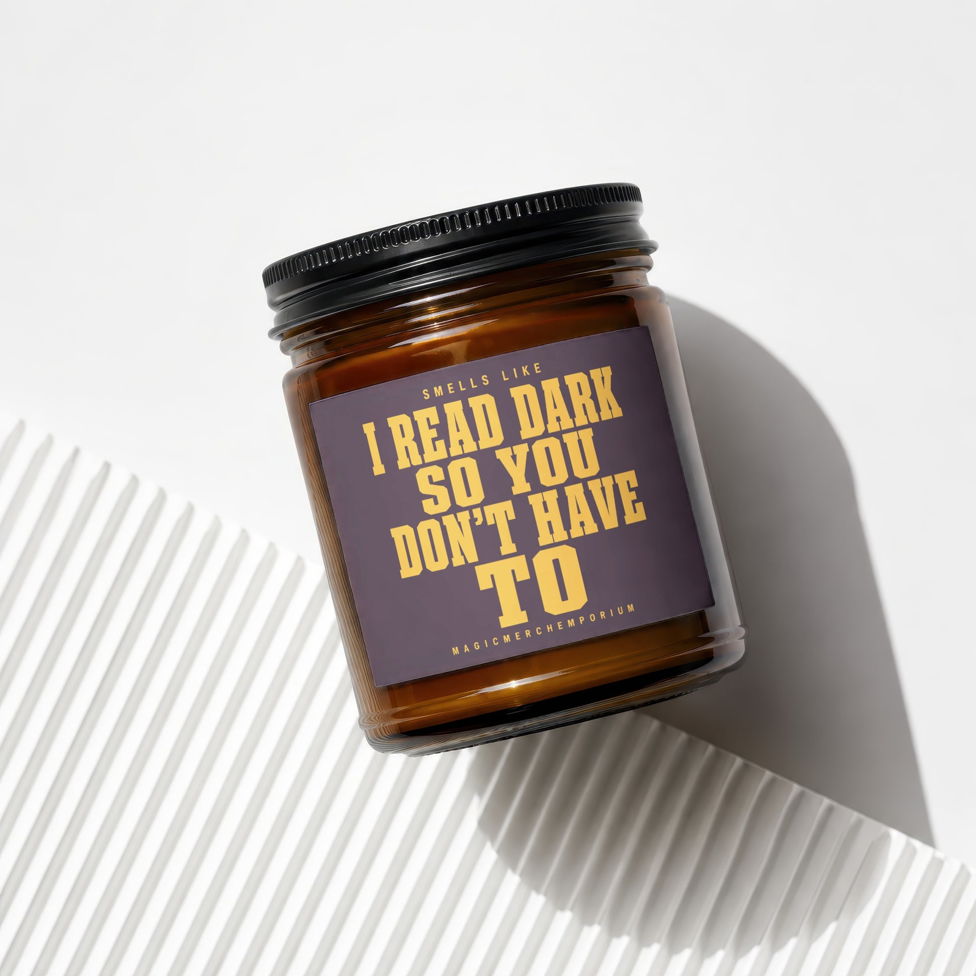 Amber glass candle with dark purple label saying "Smells like I read dark so you don't have to".