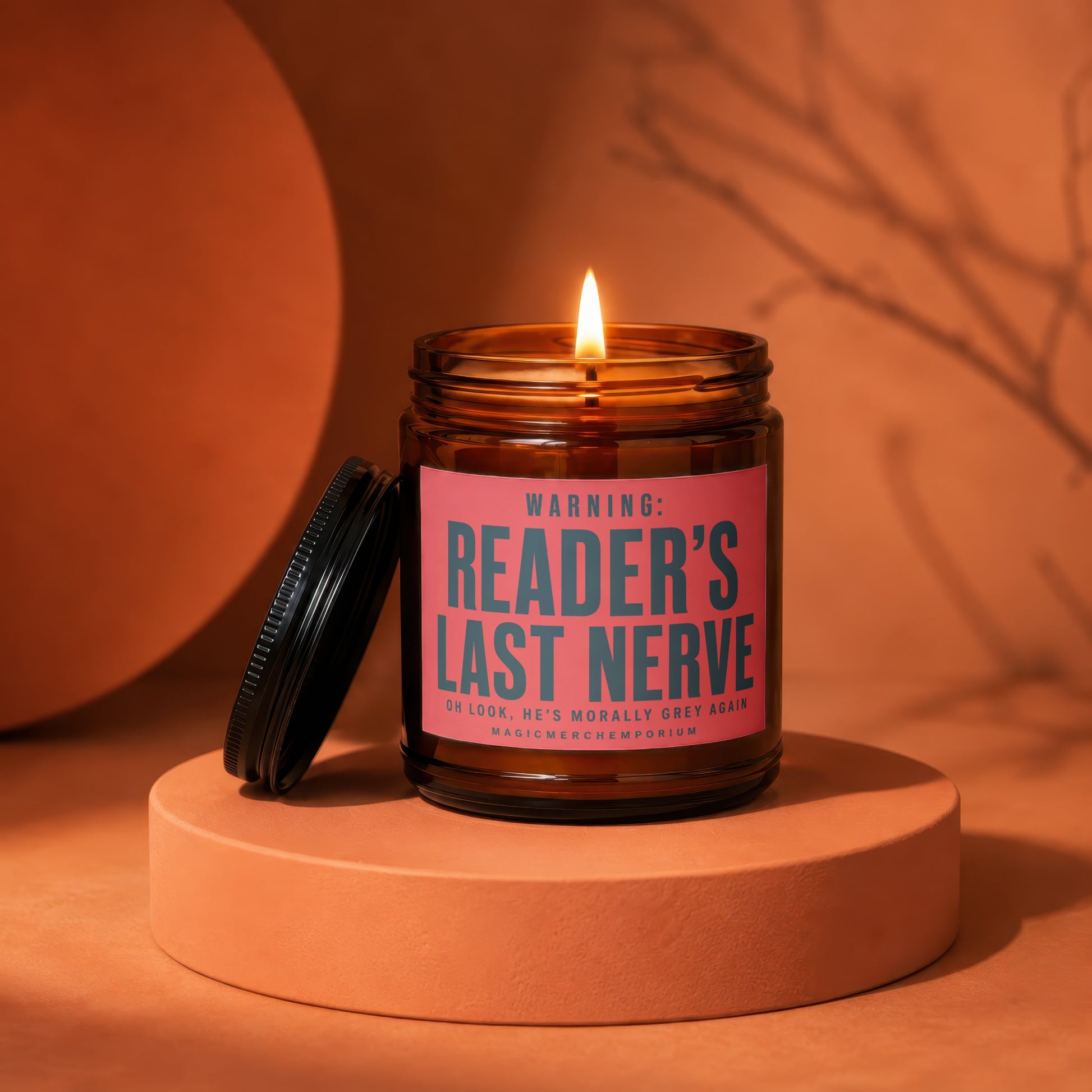 Amber jar candle with a lit flame and a pink label reading "Reader's Last Nerve."