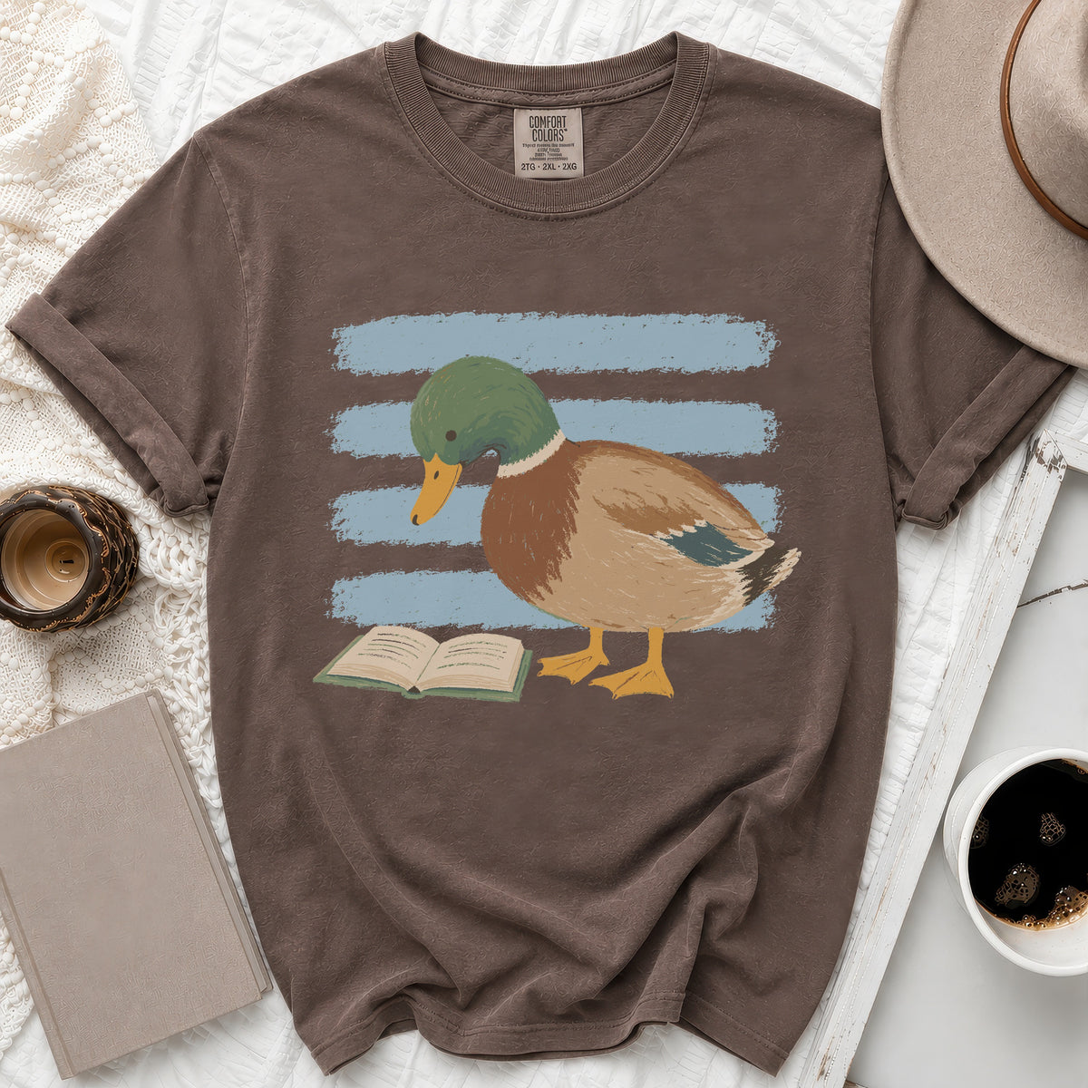 Brown t-shirt with a graphic of a mallard duck reading a book.
