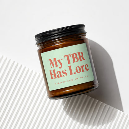 Amber jar candle with label reading "My TBR Has Lore" and "MAGICMERCH EMPORIUM".