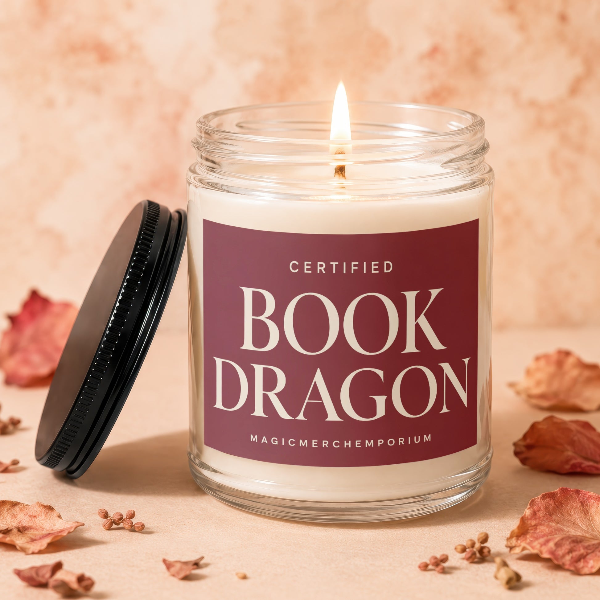 Glass jar candle with lit wick, labeled "Certified Book Dragon".