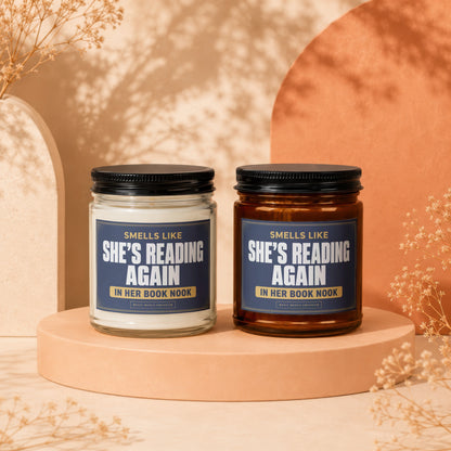 Two scented candles with labels reading "Smells like she's reading again in her book nook."