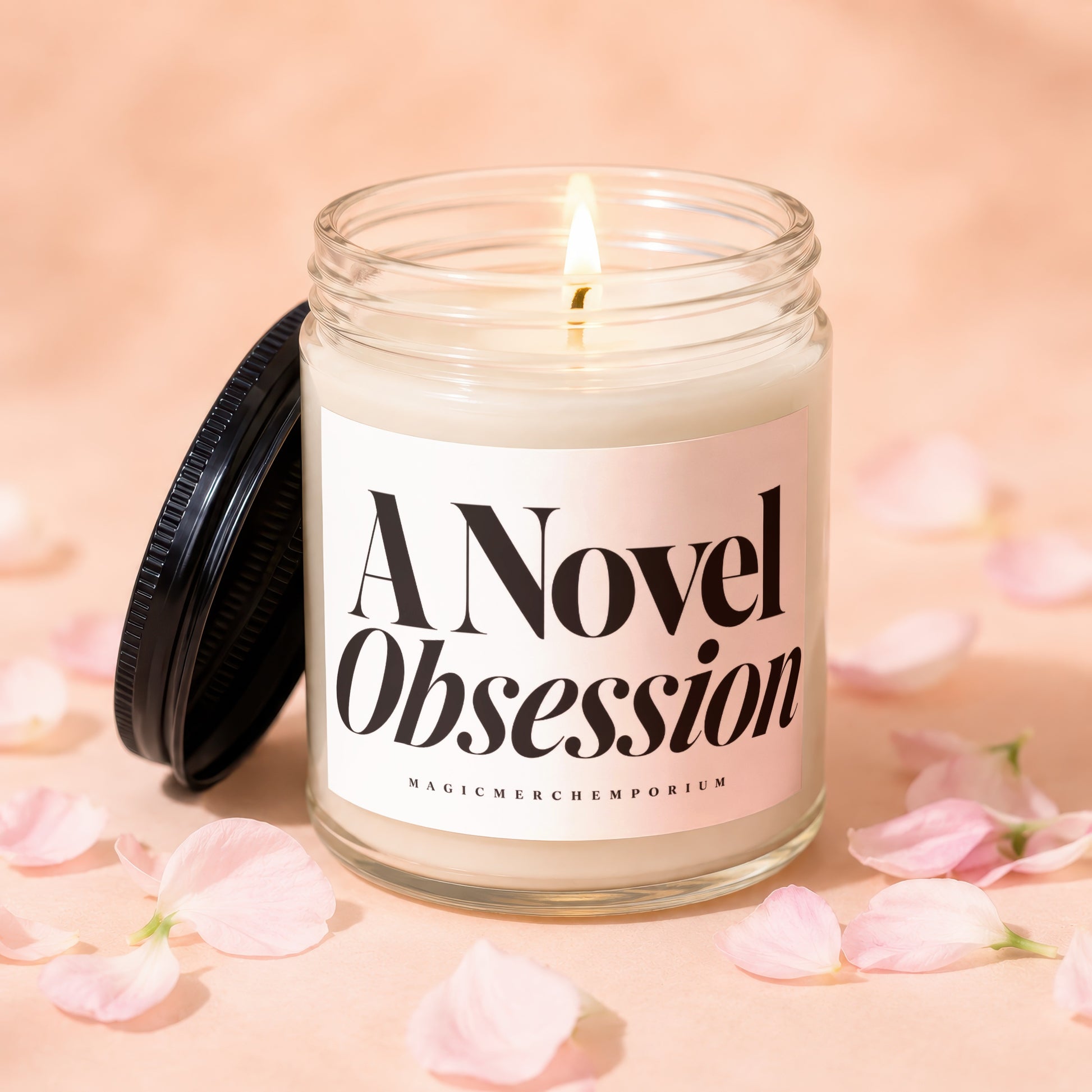 A Novel Obsession lit candle in glass jar with black lid and pink petals.