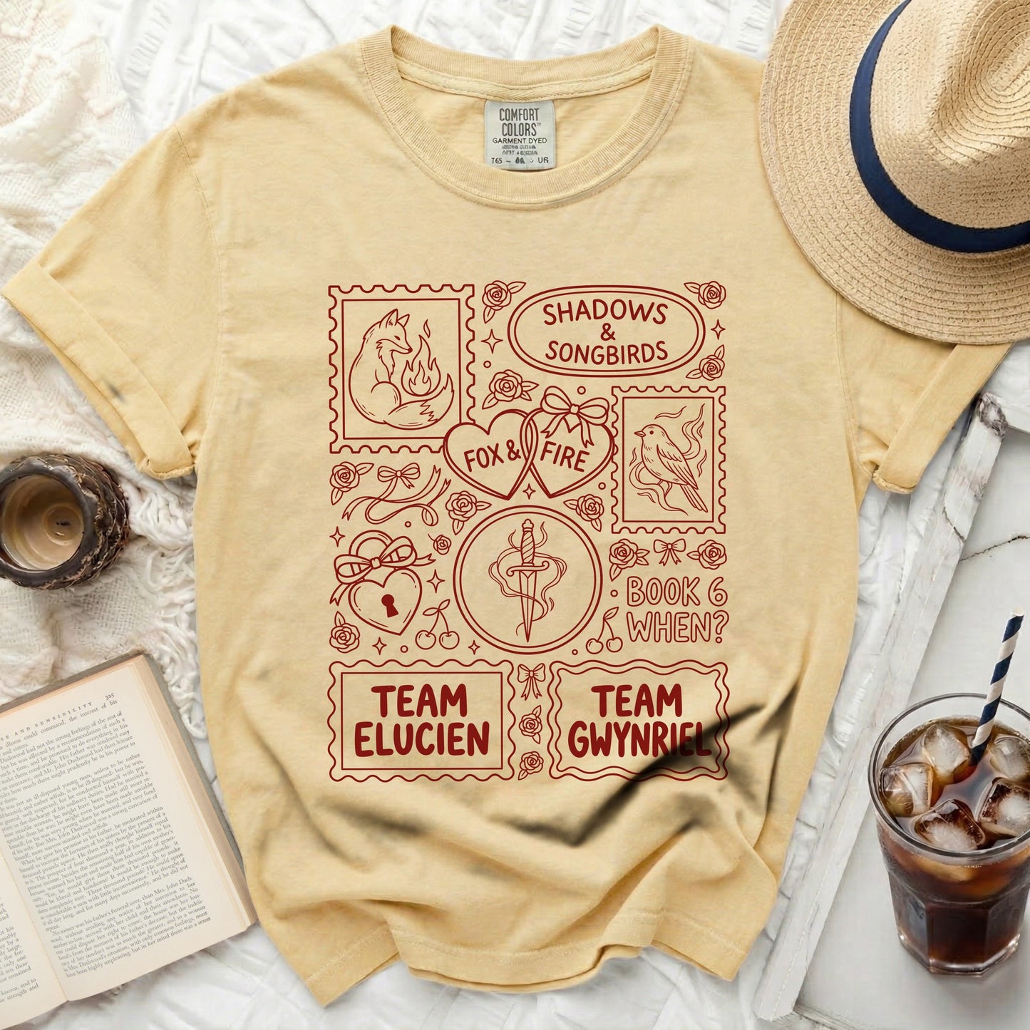 Yellow t-shirt with red graphic design featuring stamps: fox, hearts, sword, and text.