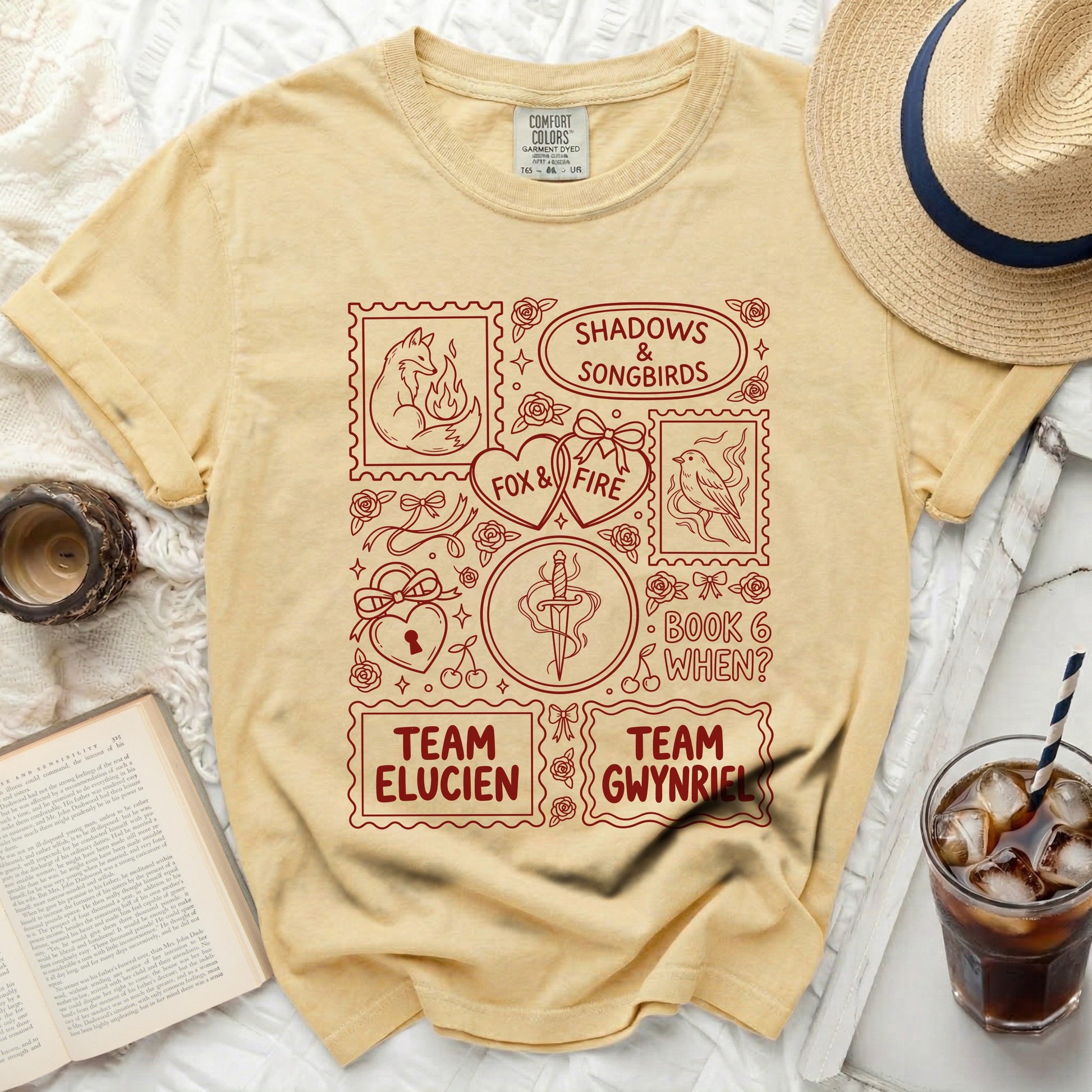 Yellow t-shirt with red graphic design featuring stamps: fox, hearts, sword, and text.
