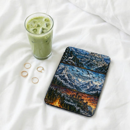 A Kindle reader with a stained-glass fantasy skin rests on white bedding next to an iced matcha latte and four gold rings.