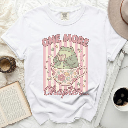 White t-shirt with a frog reading in a teacup, "ONE MORE Chapter" text.