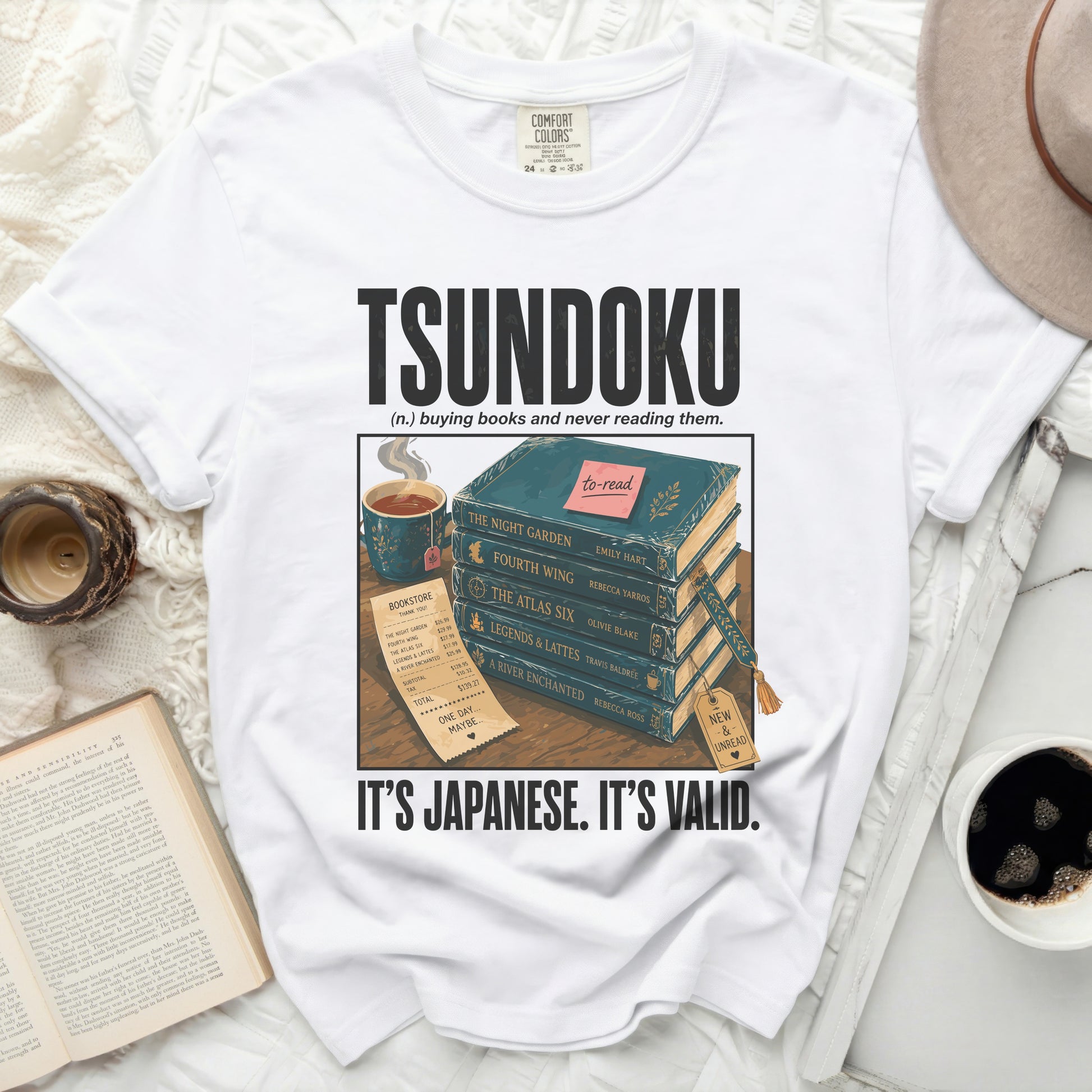 White t-shirt with "Tsundoku" text and stack of books with price list.