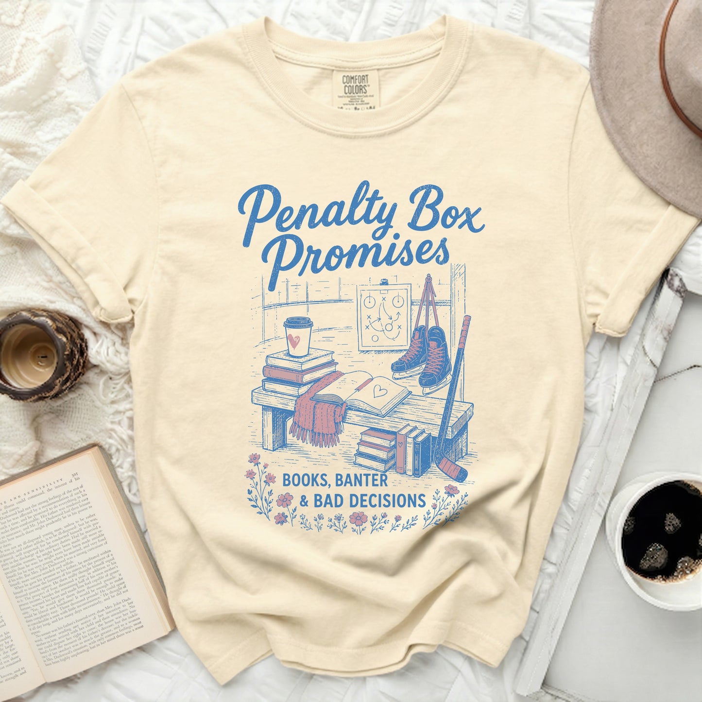 Cream t-shirt with "Penalty Box Promises, Books, Banter & Bad Decisions" text and hockey graphics.