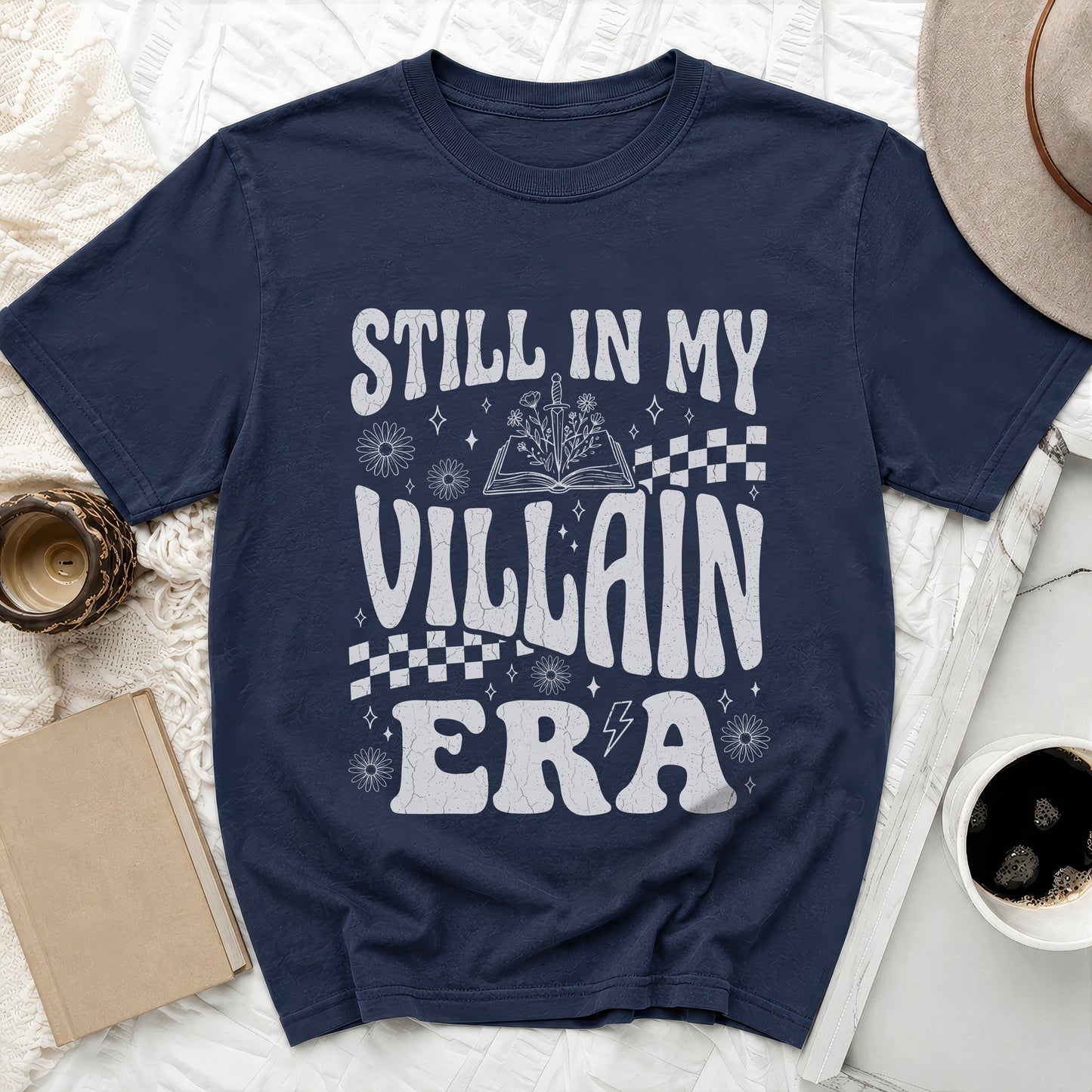 Navy t-shirt with white text "STILL IN MY VILLAIN ERA" and floral designs.