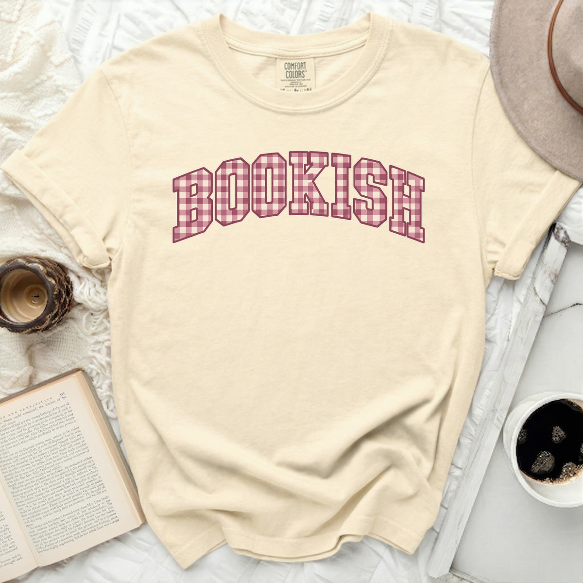 Cream t-shirt with "BOOKISH" in pink gingham letters and a Comfort Colors tag.