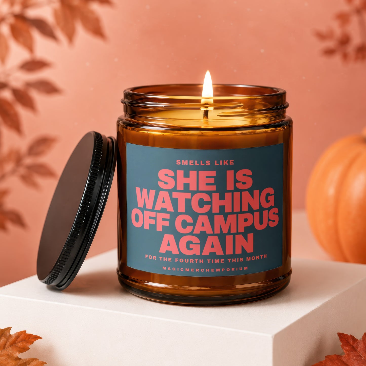 Amber jar candle with lit wick, reads "SHE IS WATCHING OFF CAMPUS AGAIN".