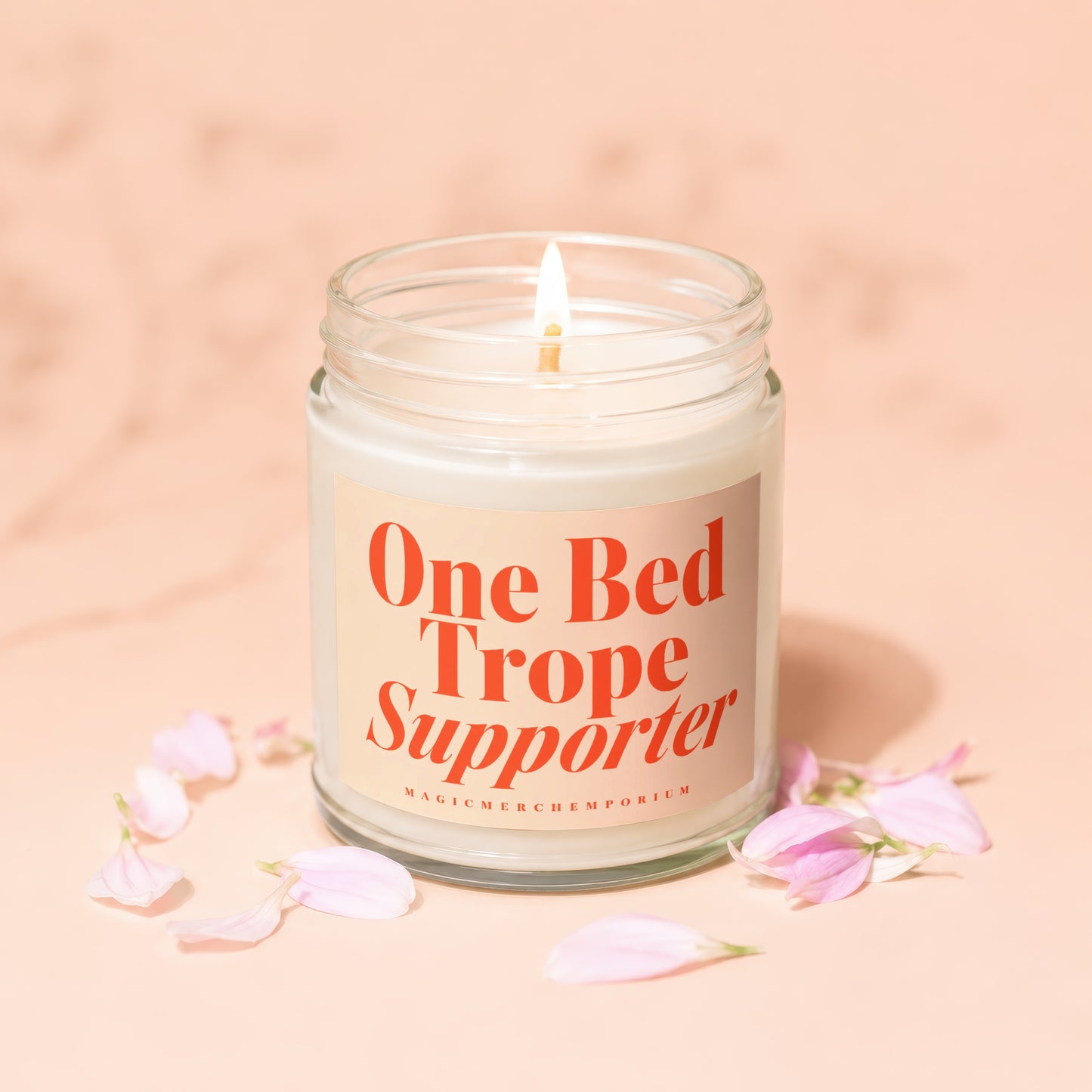 Lit candle with orange text on label reading "One Bed Trope Supporter"