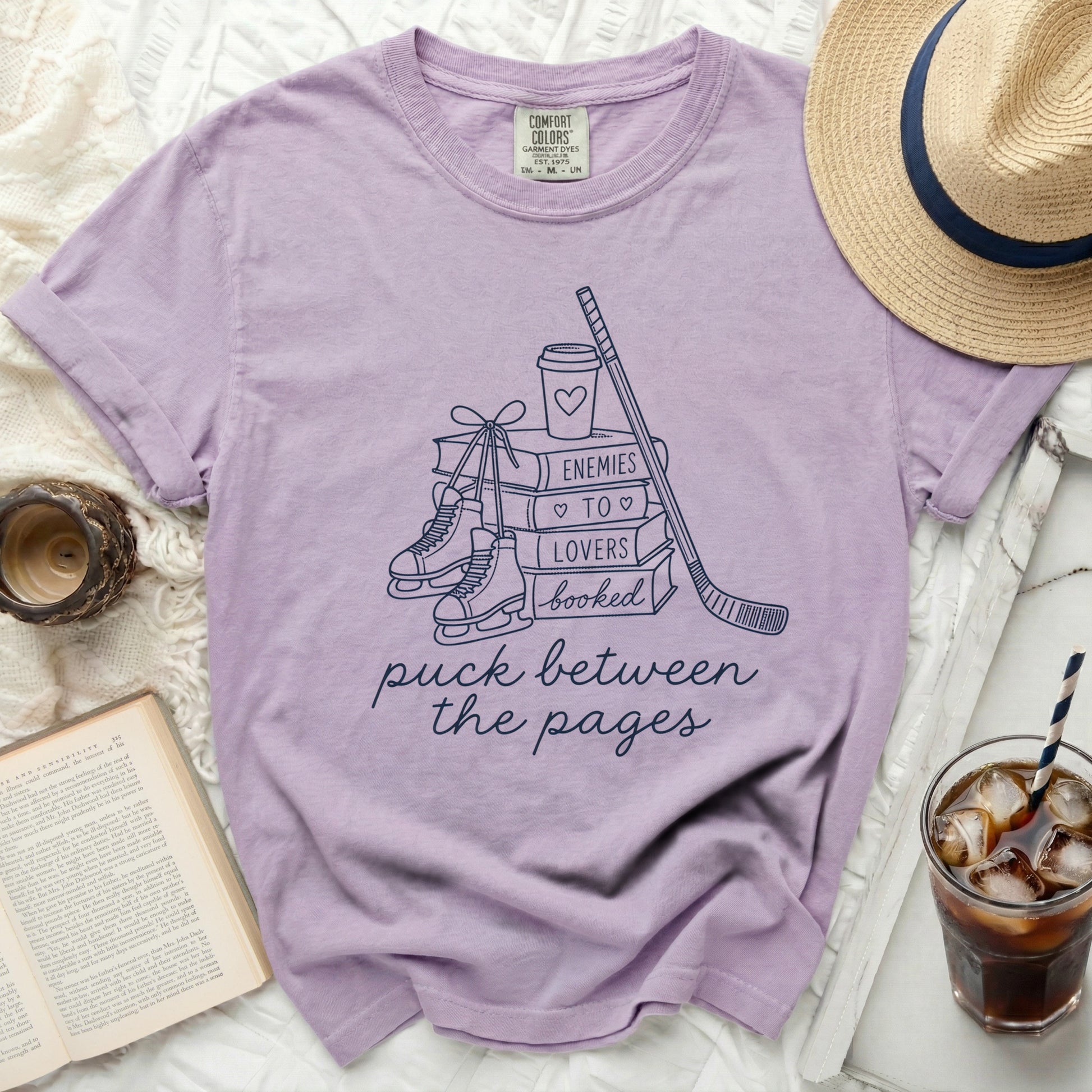 Purple t-shirt with ice skates, hockey stick, and book design.