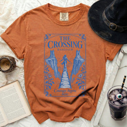 Rusty orange t-shirt featuring a blue graphic of a figure crossing a narrow bridge between cliffs.