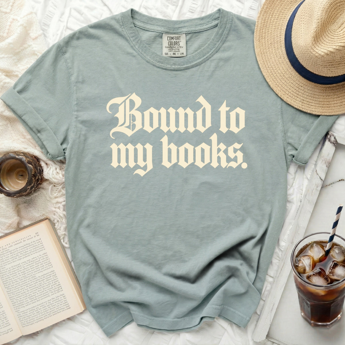 Dusty blue t-shirt with "Bound to my books." graphic print.