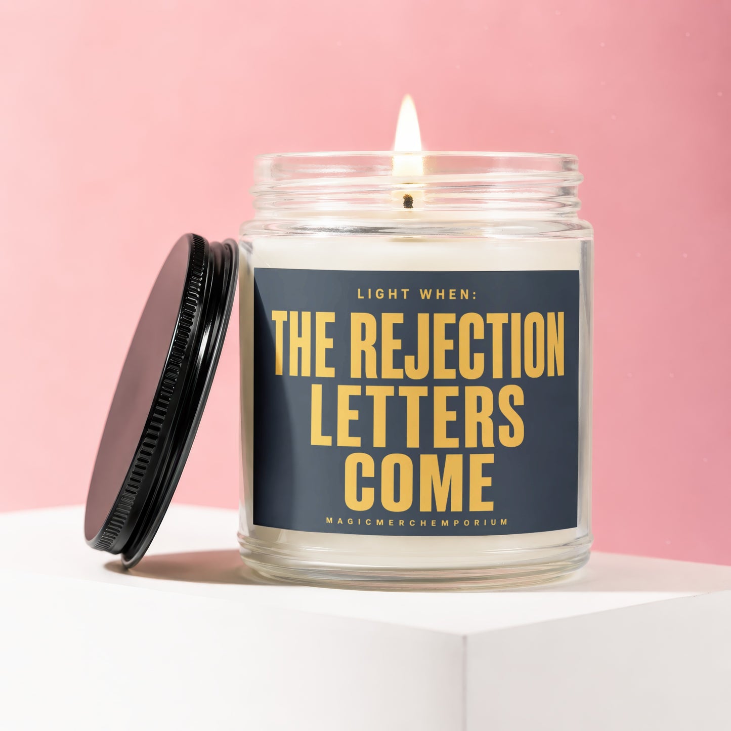 Glass jar candle with flickering flame, labeled "Light when: The Rejection Letters Come".