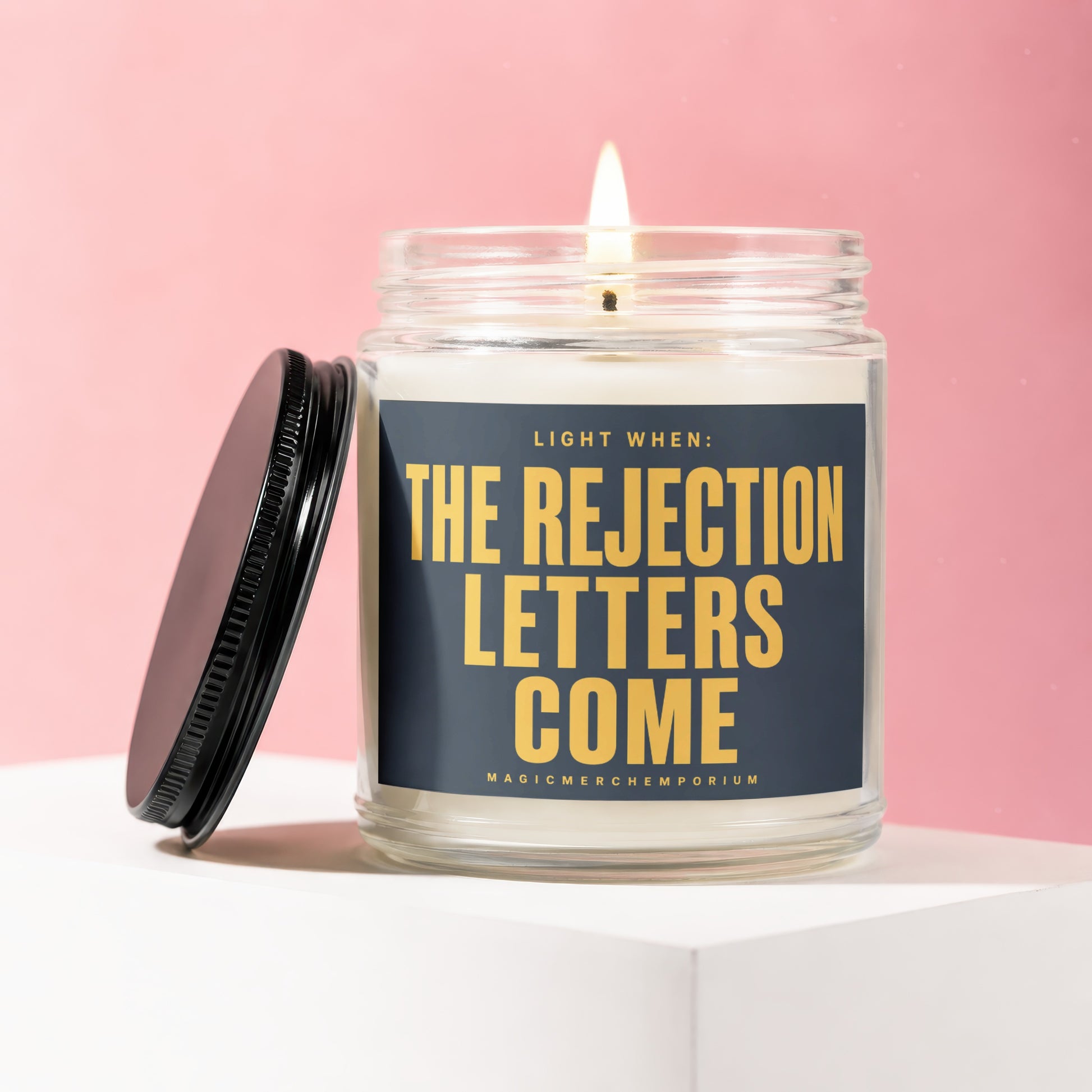Glass jar candle with flickering flame, labeled "Light when: The Rejection Letters Come".