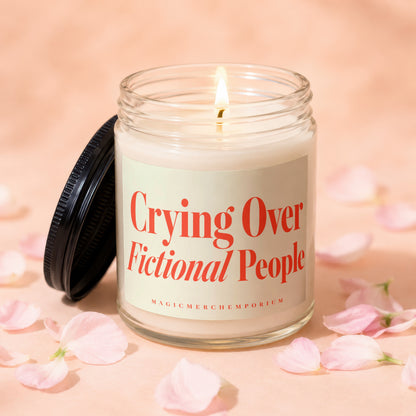 Candle with "Crying Over Fictional People" text in a glass jar with lid nearby.