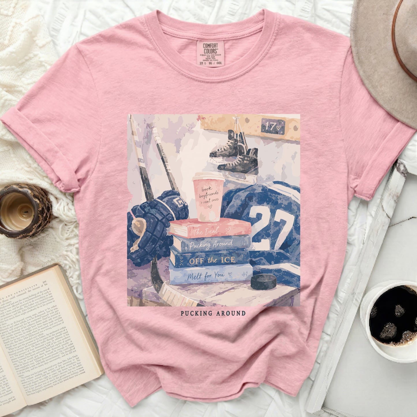 Pink t-shirt with hockey gear, books, and coffee cup, "Pucking Around" text.