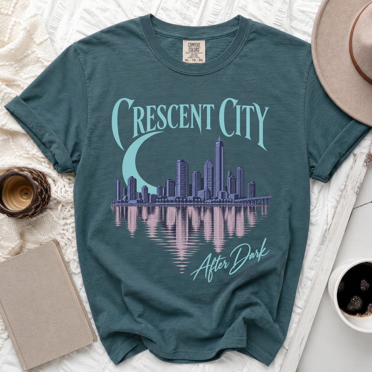 Teal t-shirt with "Crescent City After Dark" text and city skyline graphic.
