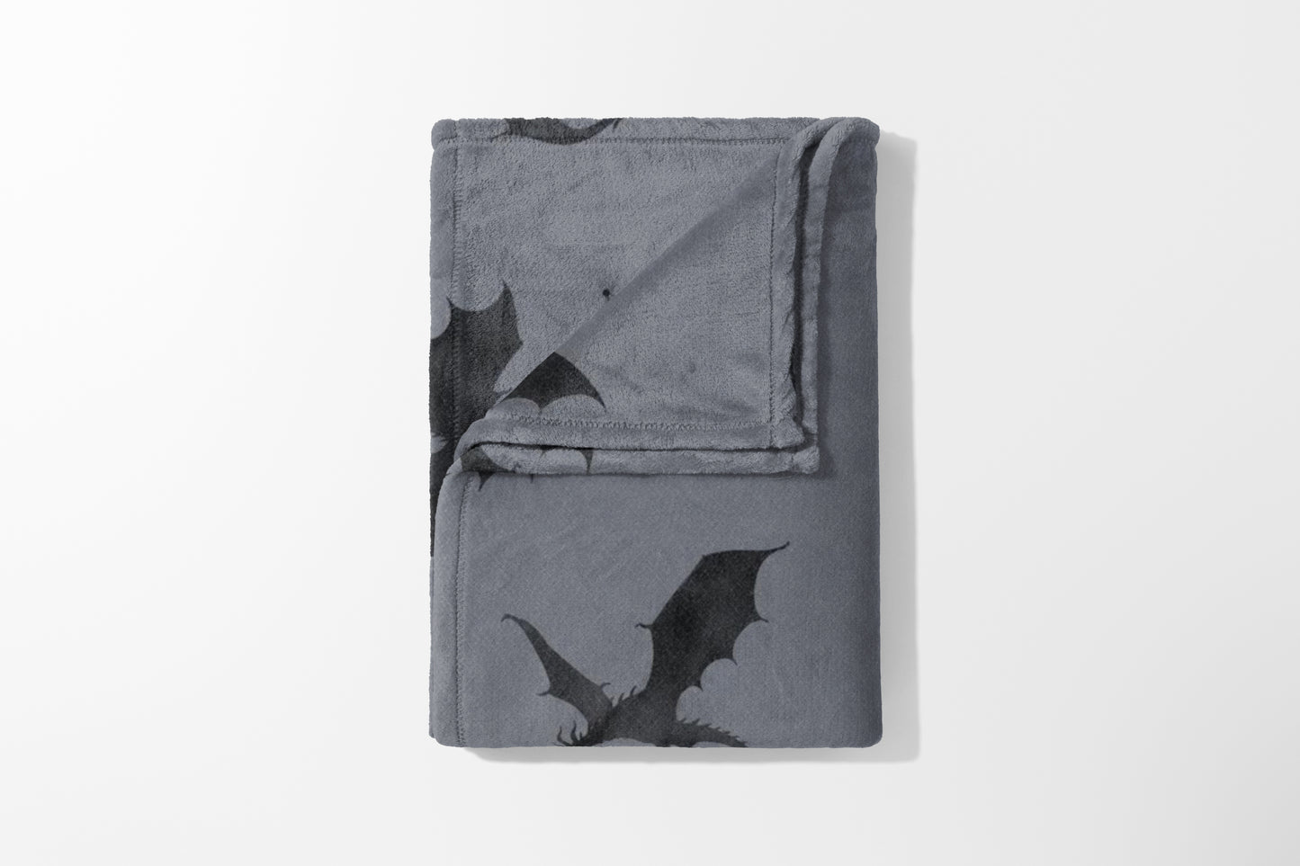 Gray fleece blanket folded with an all-over black dragon print design.