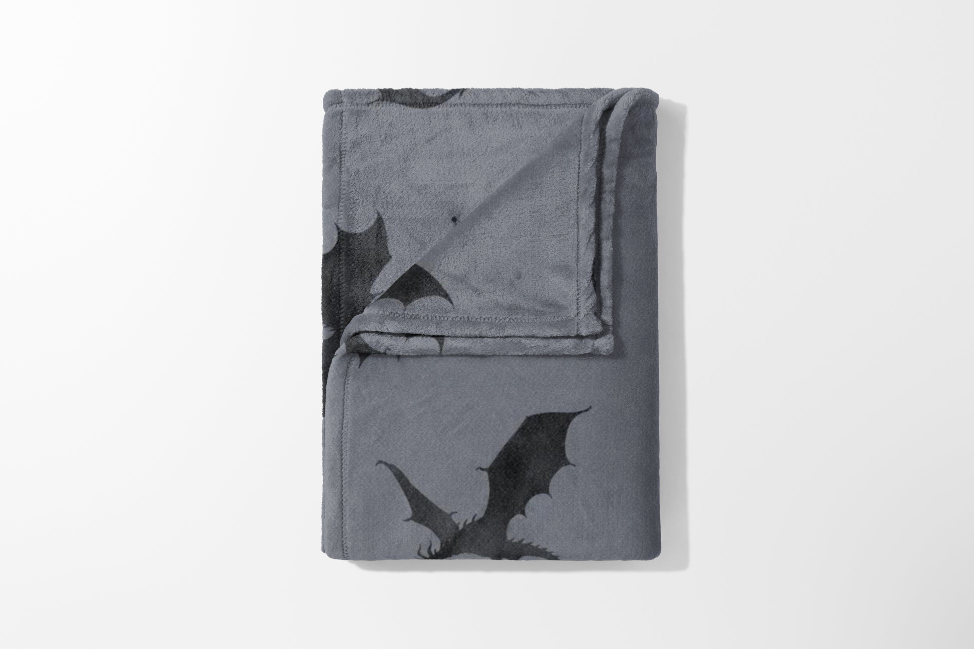 Gray fleece blanket folded with an all-over black dragon print design.