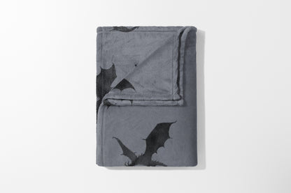 Gray fleece blanket folded with an all-over black dragon print design.