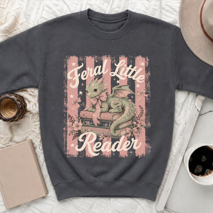 Dark grey sweatshirt with a green dragon on books, text "Feral Little Reader".