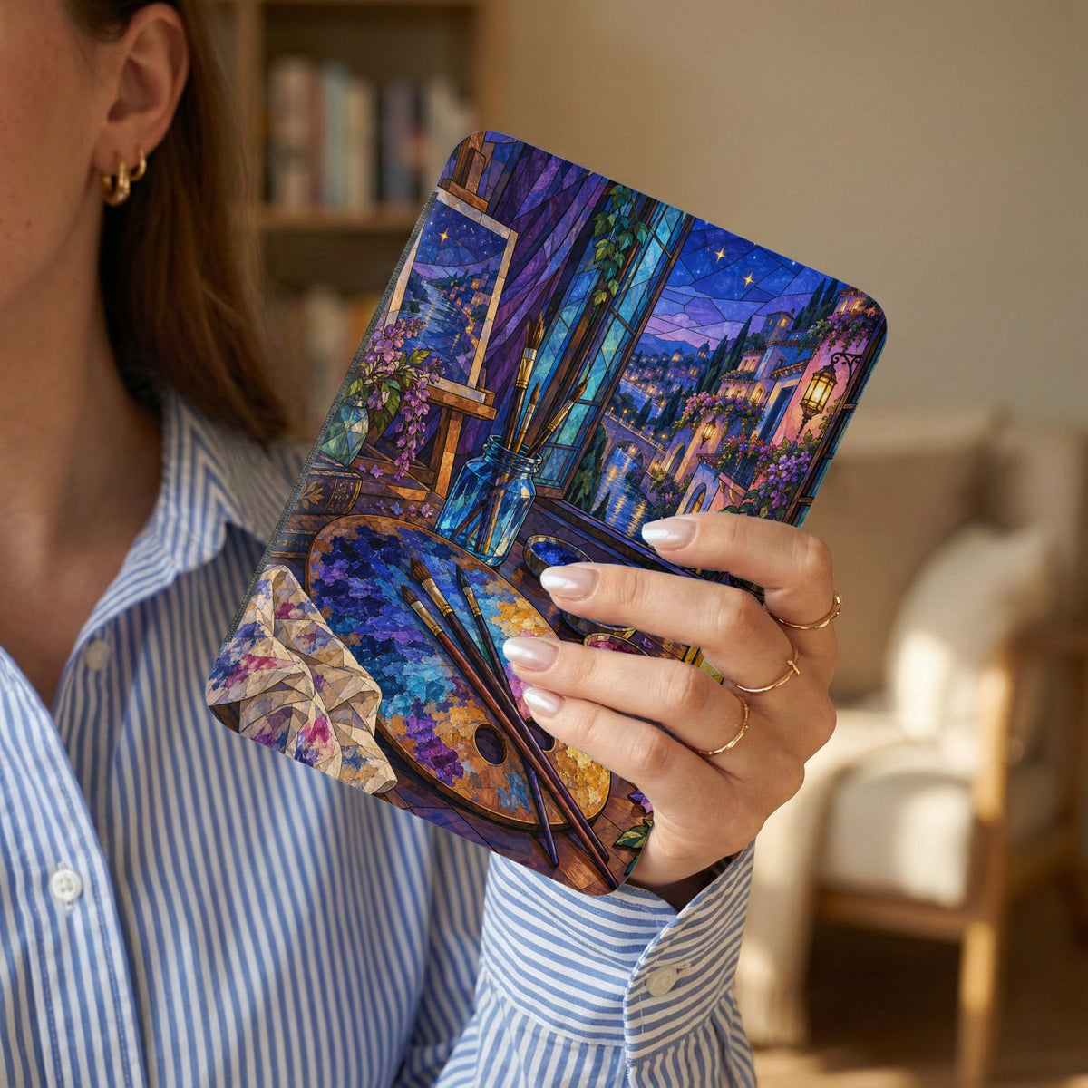 Case featuring a stained-glass style painting of a European town and art supplies.
