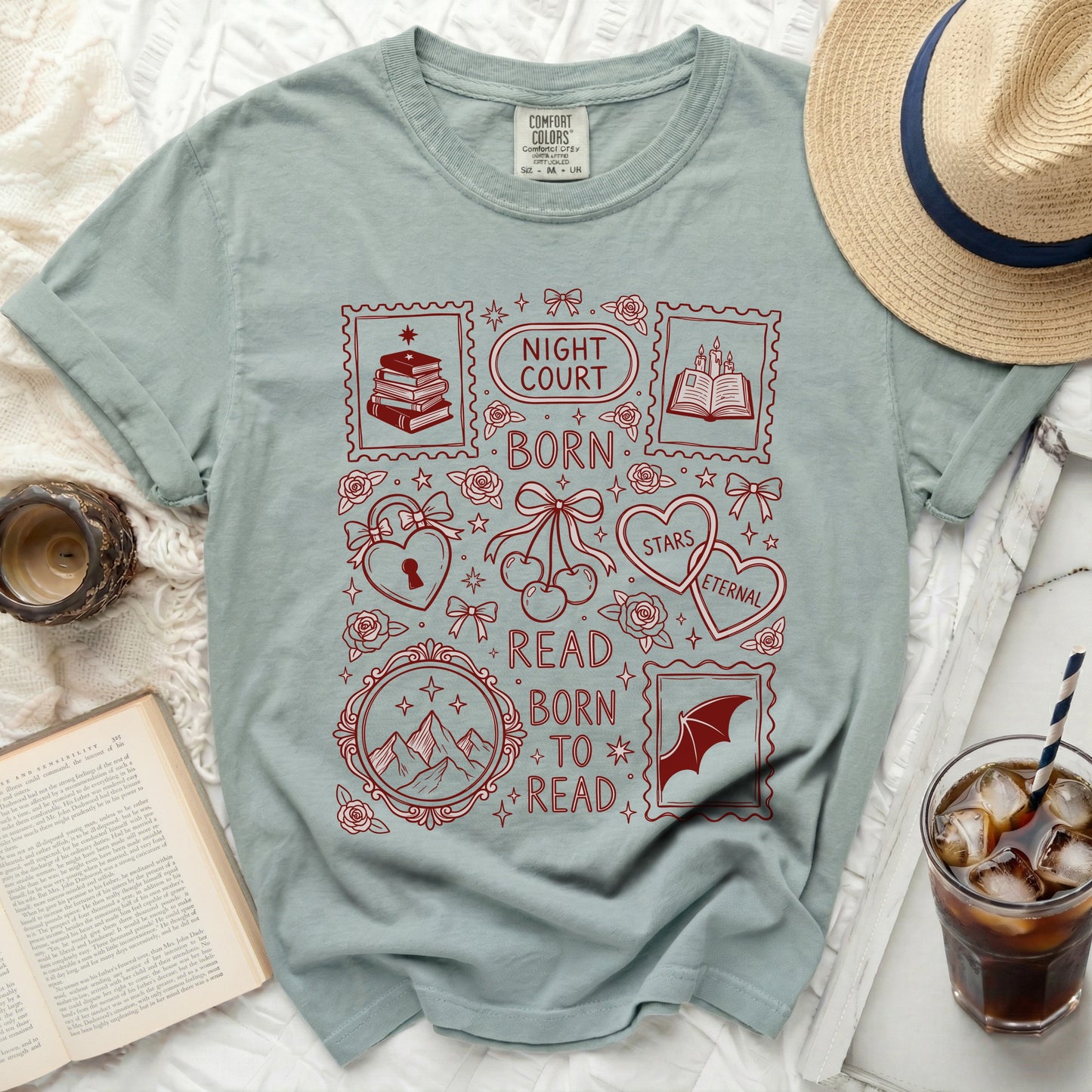 Light sage green t-shirt with red graphic featuring stamps, books, mountains, and text.
