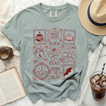 Light sage green t-shirt with red graphic featuring stamps, books, mountains, and text.