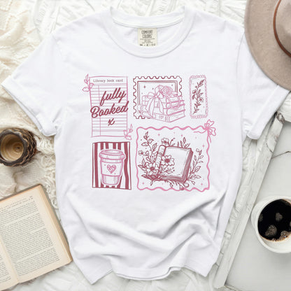 White t-shirt with pink graphic of books, coffee cup, and "fully Booked" text.