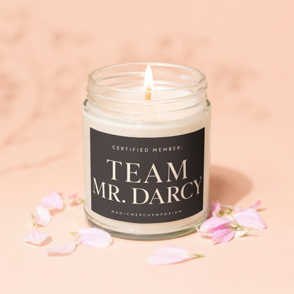 Lit candle in glass jar with "Team Mr. Darcy" label, surrounded by pink petals.