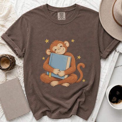 Brown t-shirt with a monkey hugging a blue book and yellow stars.