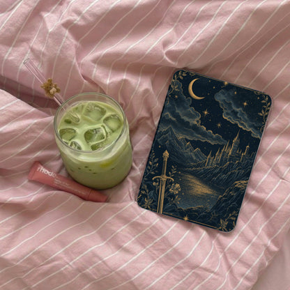 Glass of iced matcha, lip balm, and a celestial castle phone case on pink striped fabric.