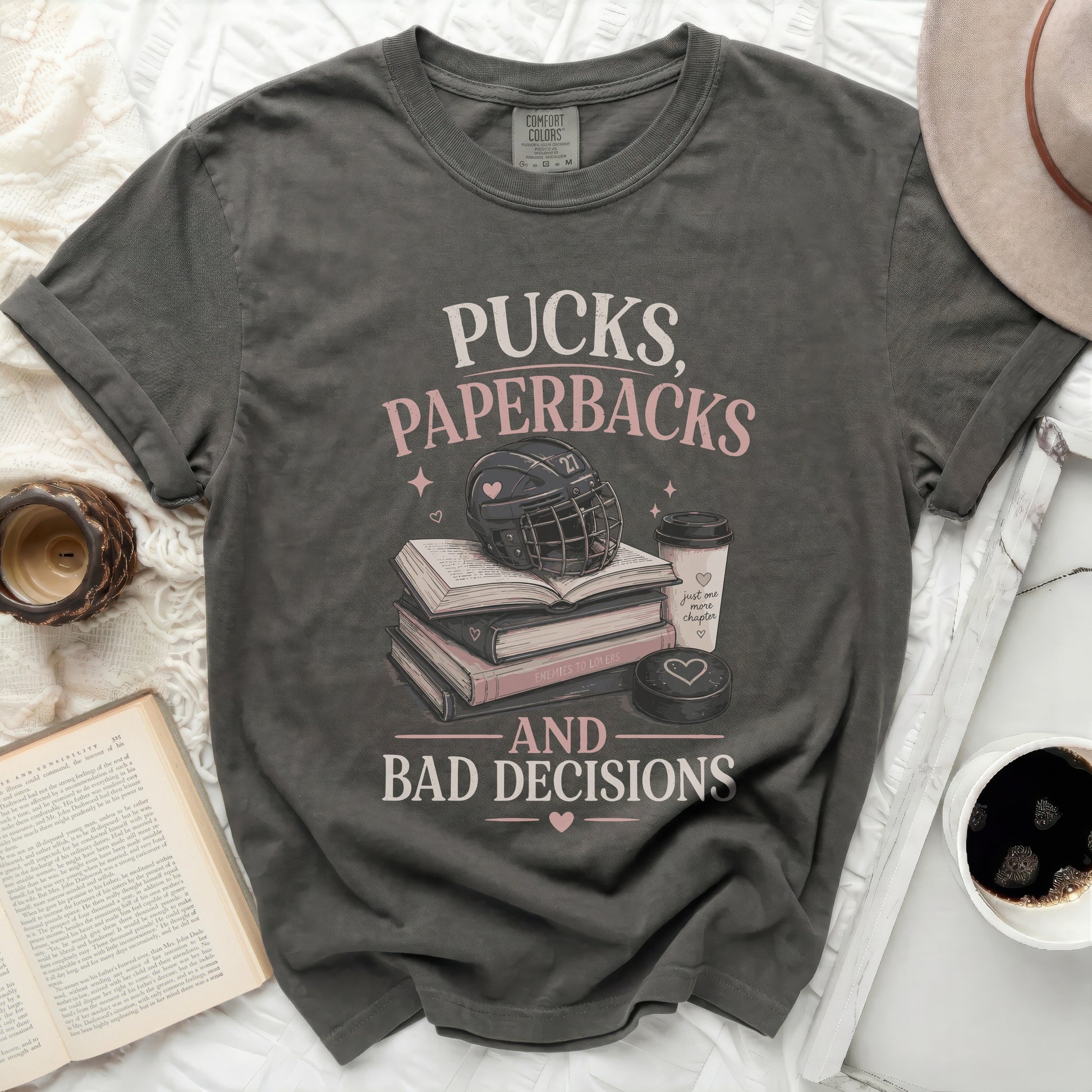 T-shirt with "Pucks, Paperbacks, and Bad Decisions" text, hockey puck, and books.
