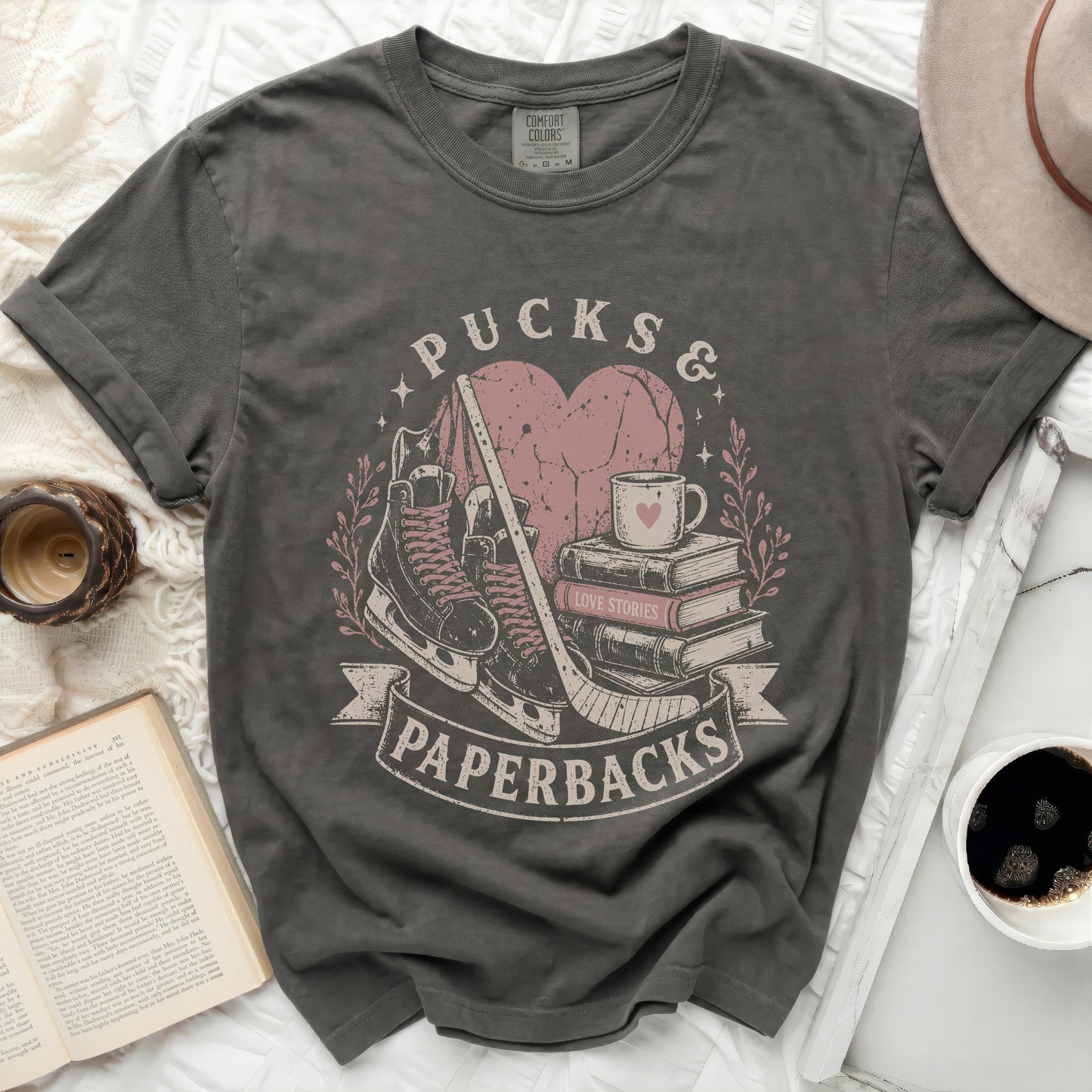 Dark gray t-shirt with "Pucks & Paperbacks" text, hockey skates, and books.