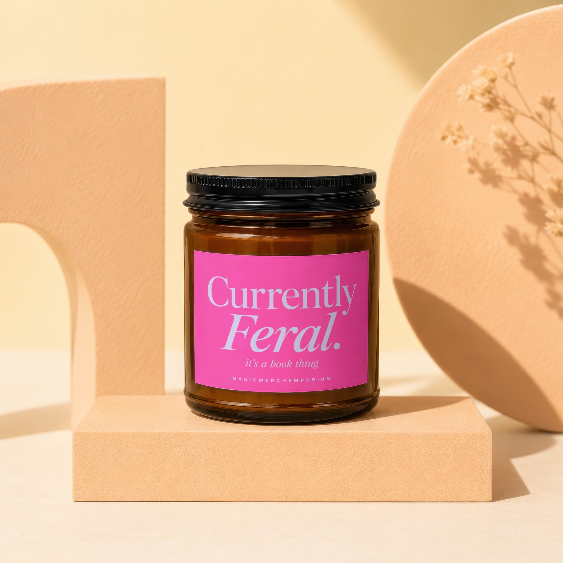 Amber jar candle with pink label that reads "Currently Feral. it's a book thing".