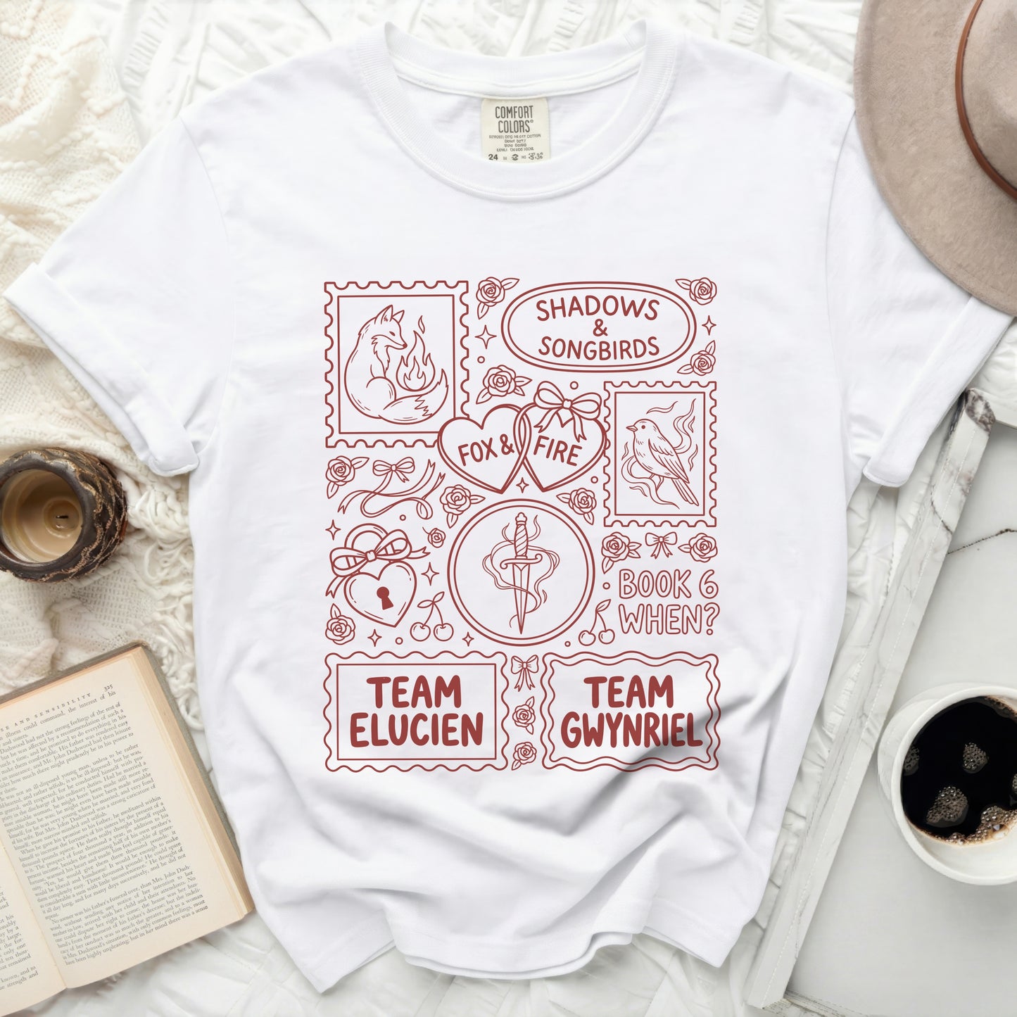White t-shirt with red graphic of stamps, fox, birds, hearts, dagger, and text.