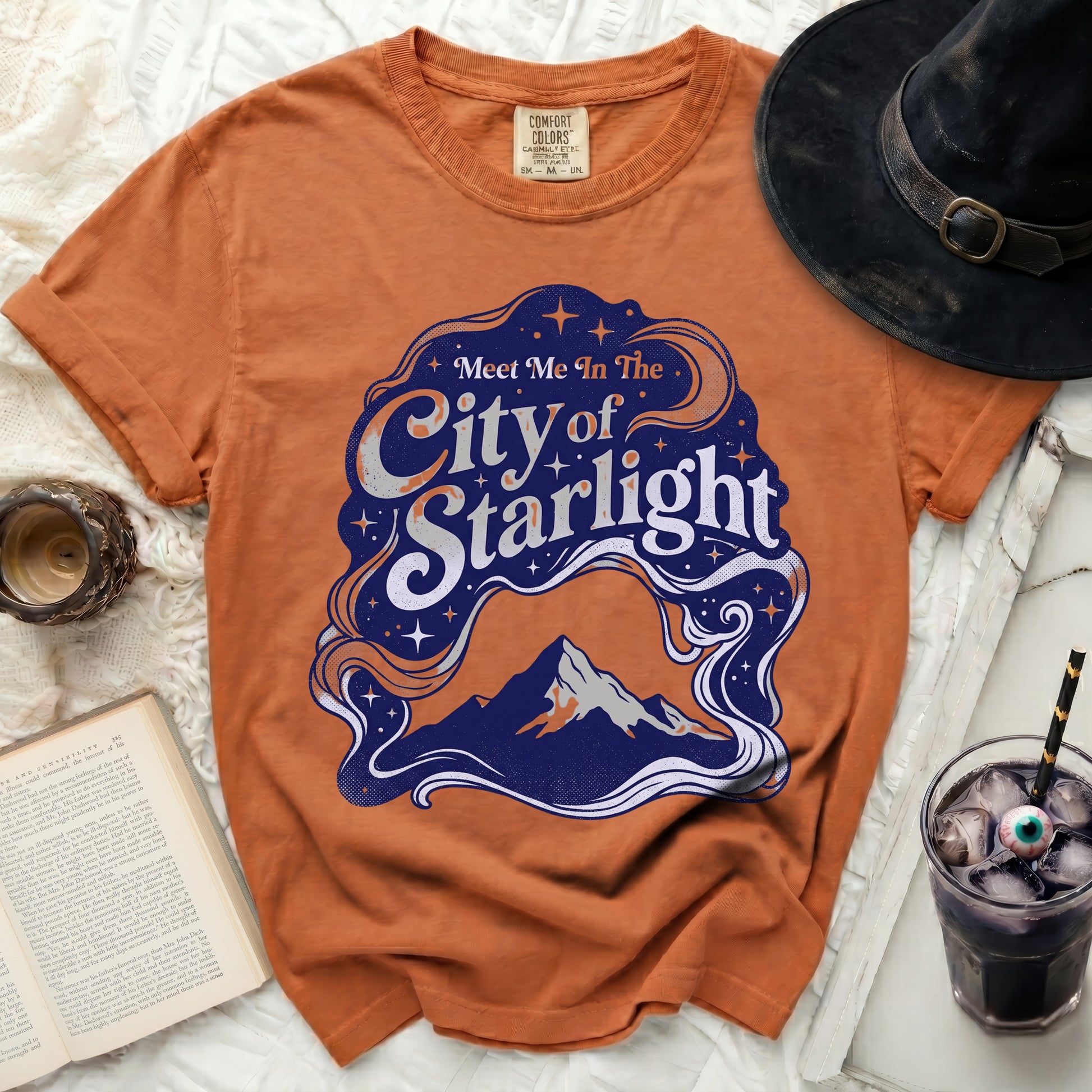 Orange t-shirt with "Meet Me In The City of Starlight" graphic.