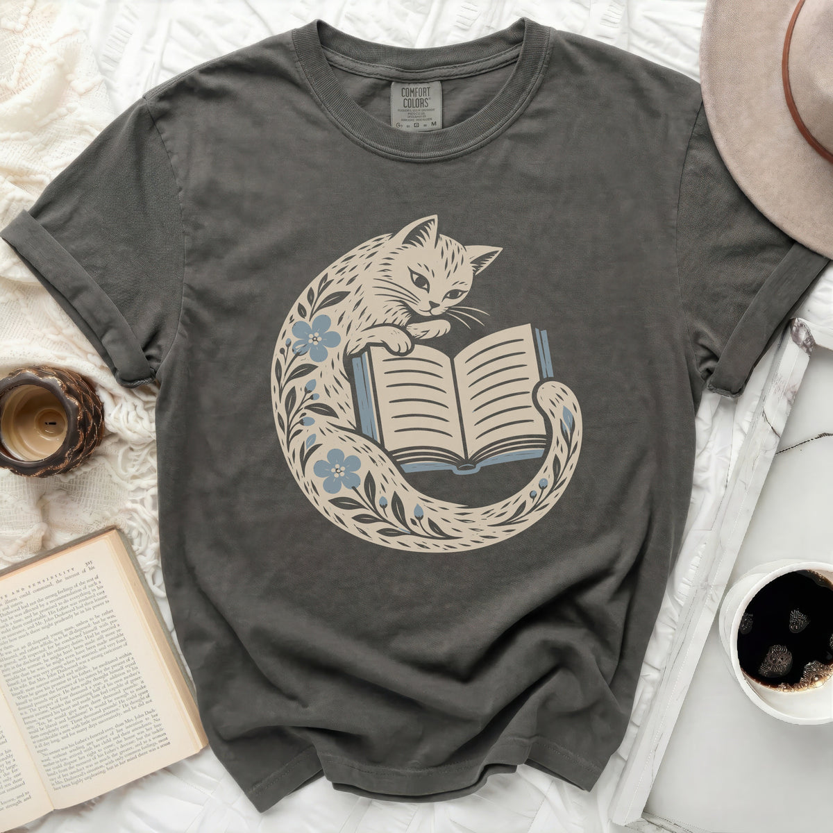 Dark grey t-shirt with a cream cat reading a book, surrounded by blue flowers.