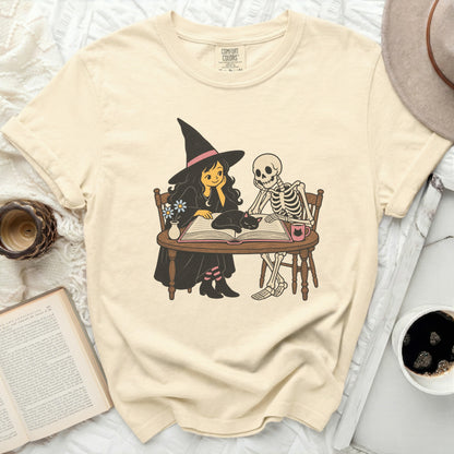 Witch, skeleton, and cat reading a book together.