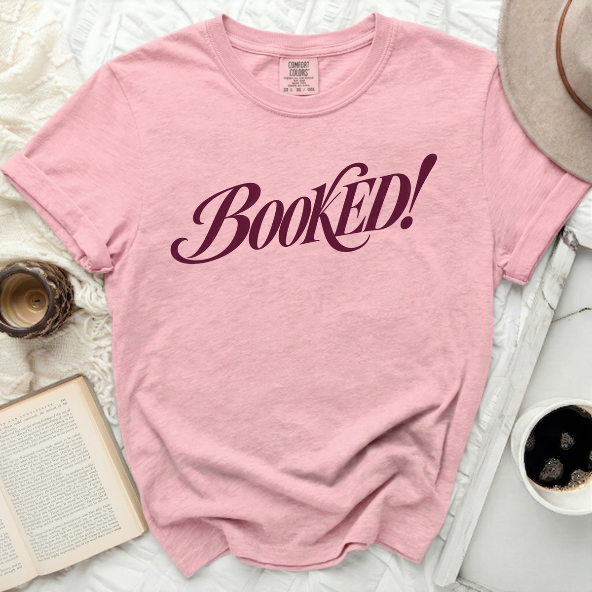 Pink t-shirt with "Booked!" text in maroon script, Comfort Colors brand.