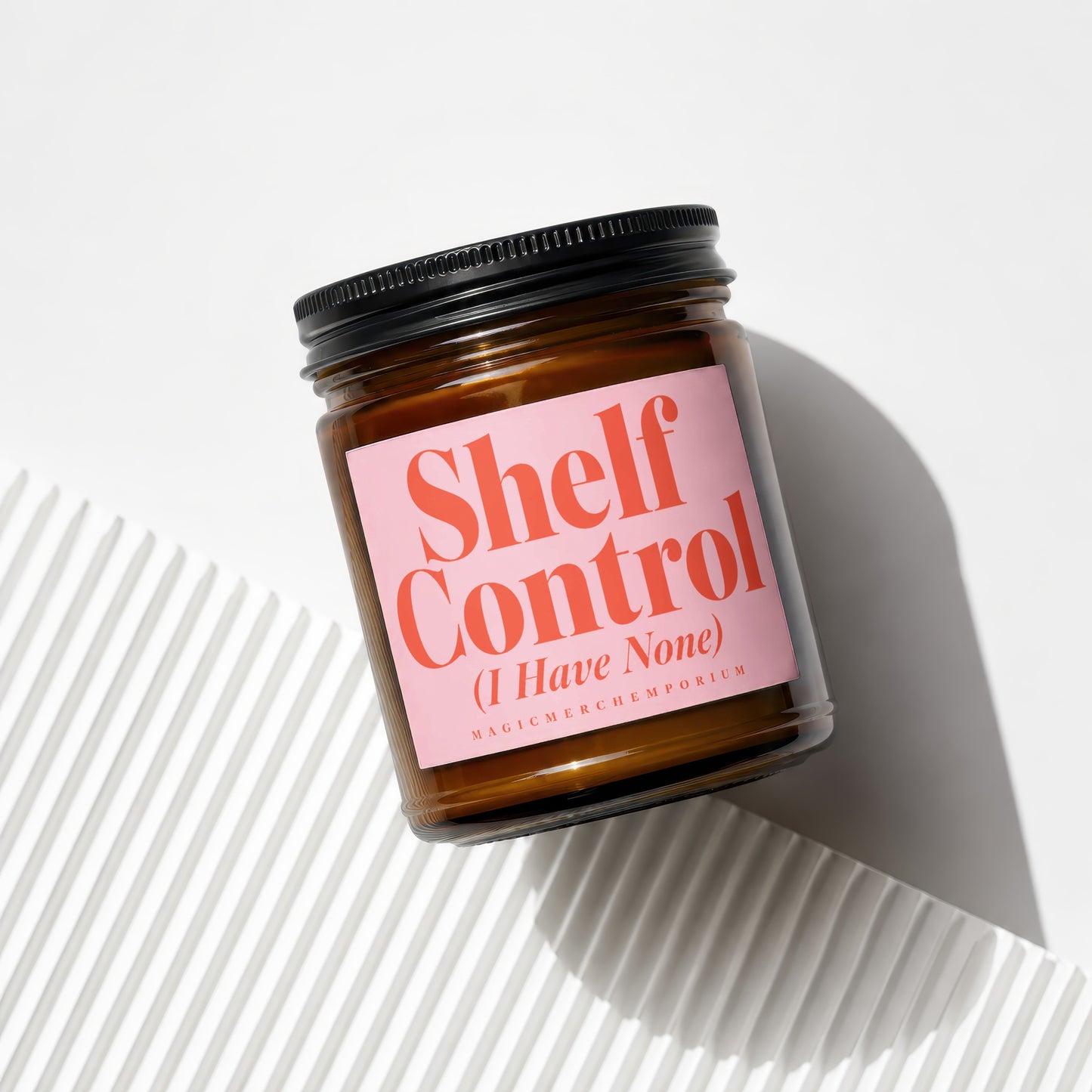 Brown jar candle with pink label reading "Shelf Control (I Have None)".